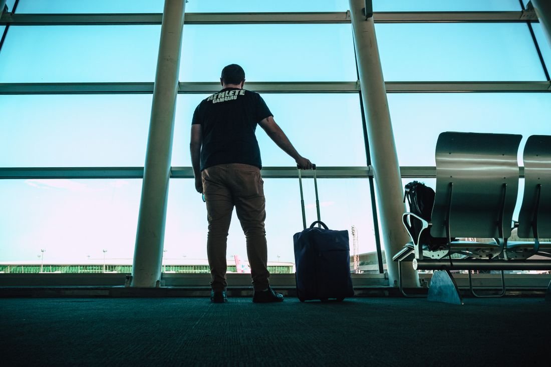 A student waiting with luggage at an airport departure gate